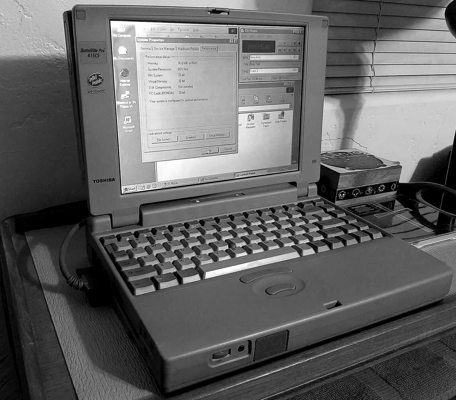 An old gray Toshiba Satellite laptop resting on a wooden table